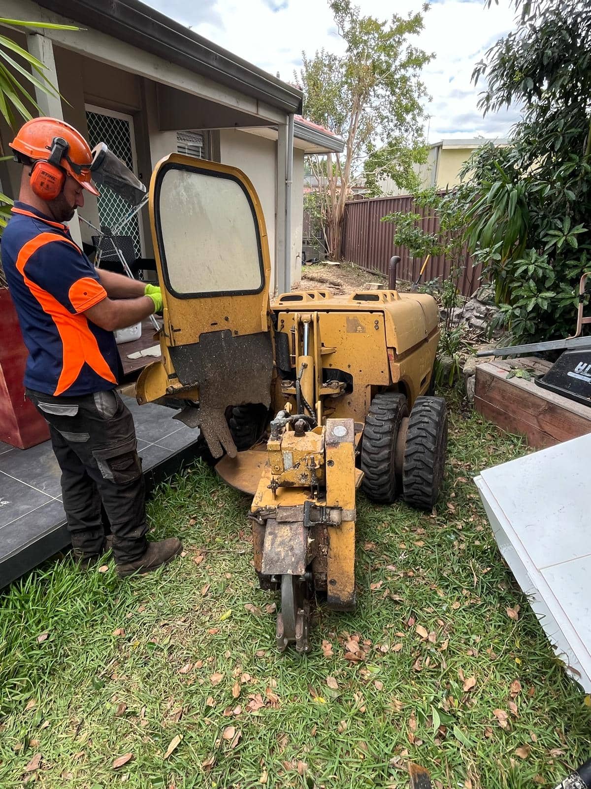 Narrow-access stump grinder set up beside a Sydney home for backyard stump removal