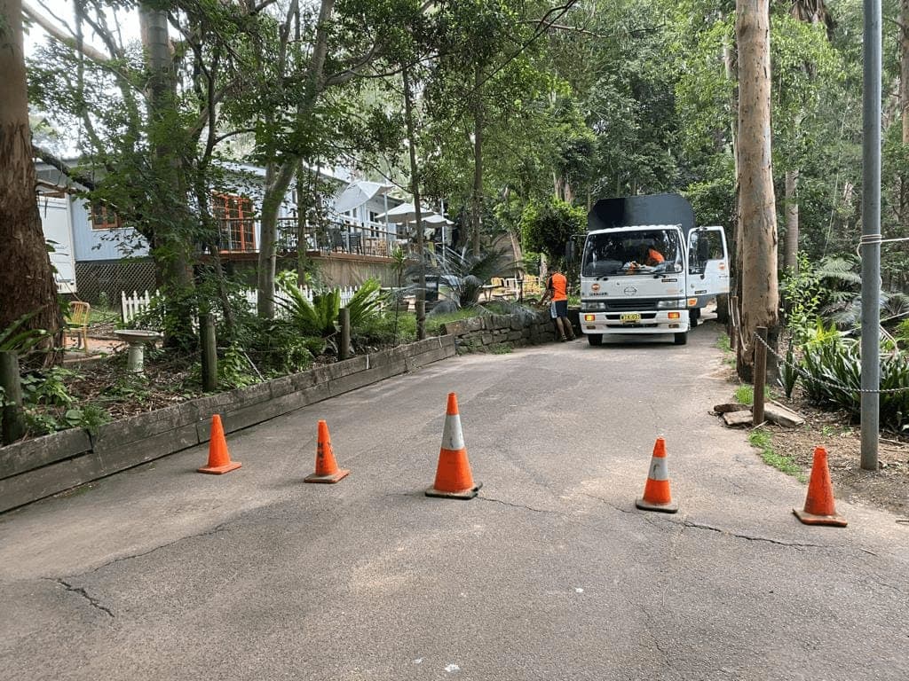 Chip truck with safety cones on a narrow tree-lined road